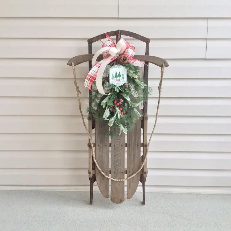 Place the decoration with a sleigh upright and decorate it with a wreath or arrangement