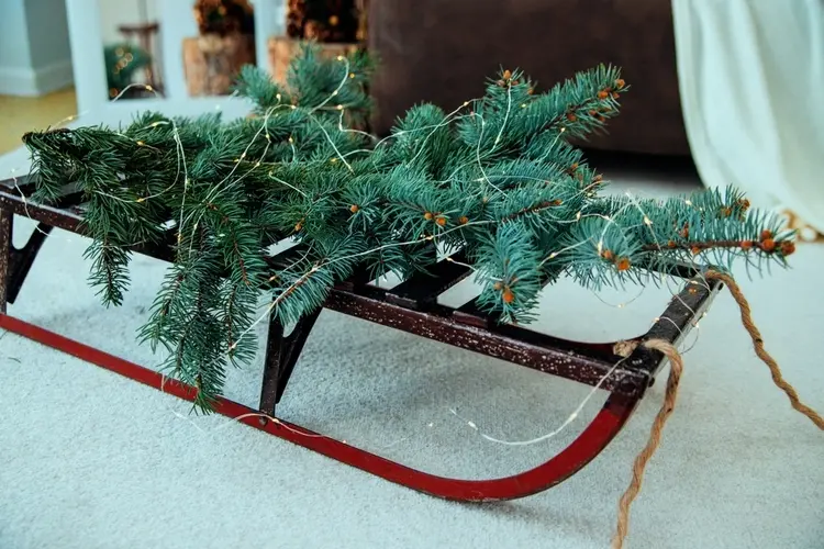 Distribute decorations with sleighs in the living room in fir green and decorate with fairy lights