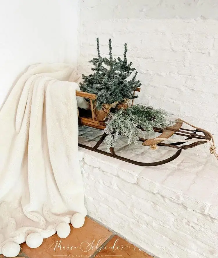 Arrange decoration with sleigh inside with cozy blanket and fir trees